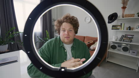 man talking excitedly on camera as recording video content with ring light