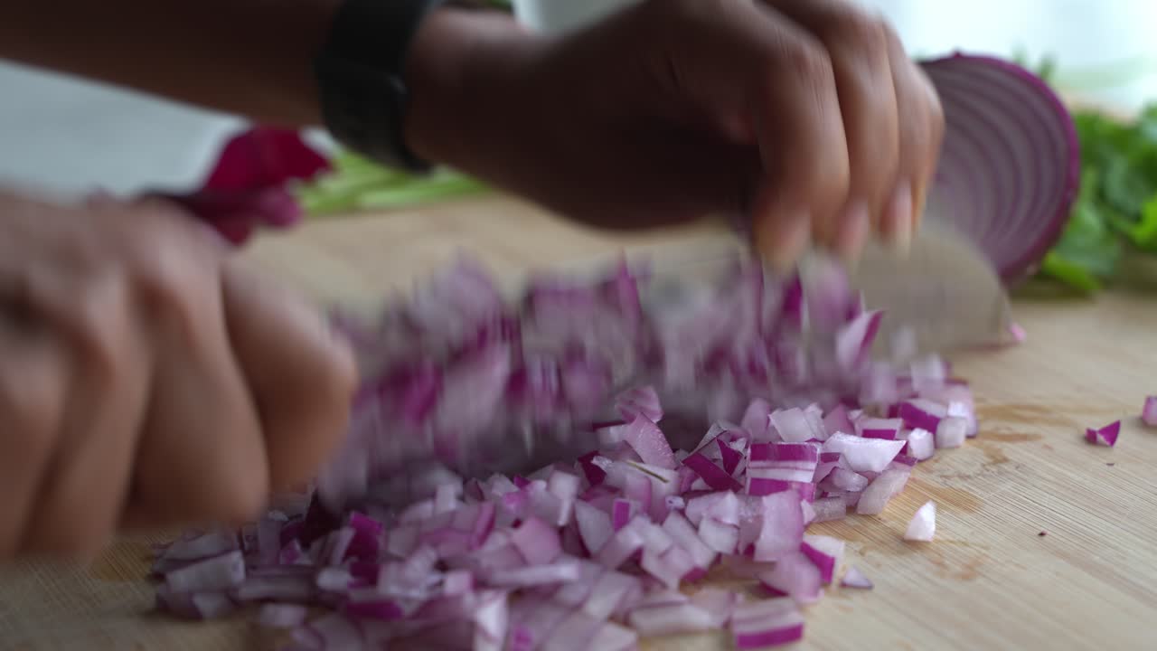 Chopping onions using a sharp knife and special ingredients to cook a meal two cans of beans rice plantain avocado red onion and cilantro