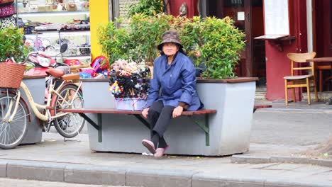 woman in blue coat near flowers and bicycles