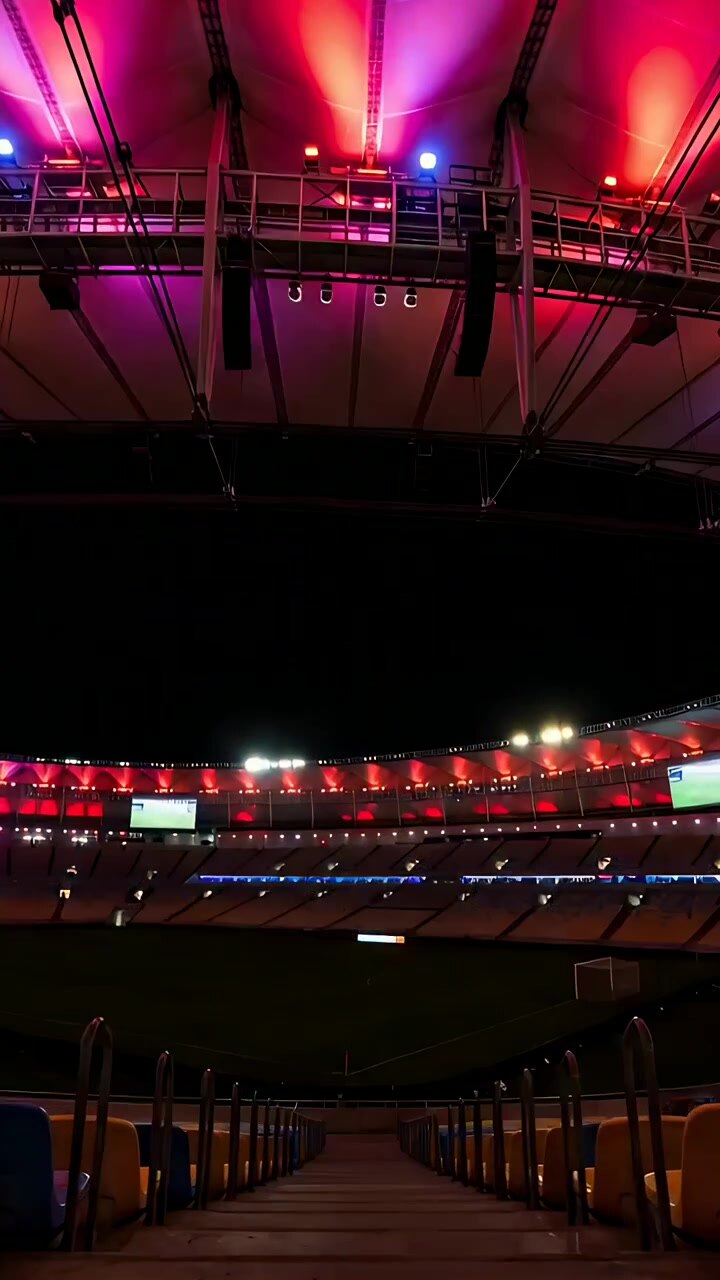 Vertical video: Floodlights dimming causing cam centering arena down stairs to soccer pitch glowing