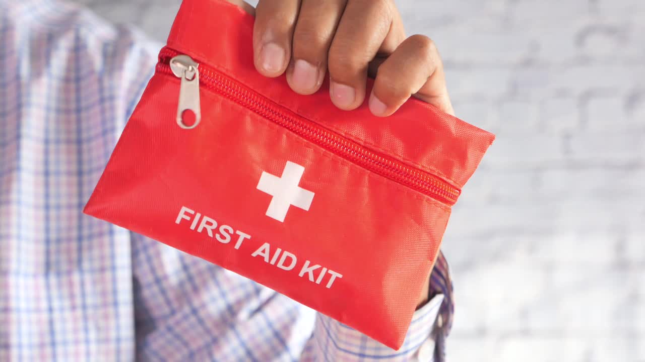 빨간색 응급 처치 상자를 들고 있는 손