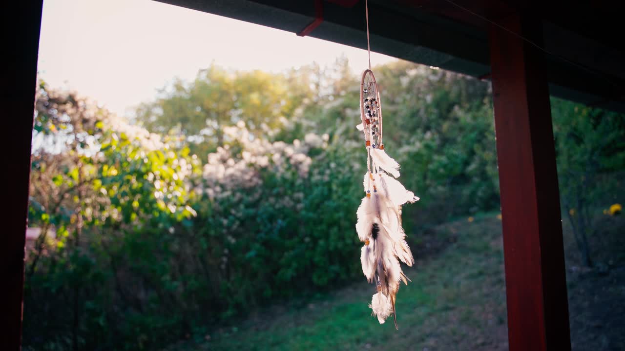 털과 돌로 인 드림캐처가 베란다에 매달려 있습니다.
