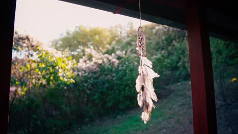 un cazador de sueños tejido con plumas y piedras cuelga en la terraza