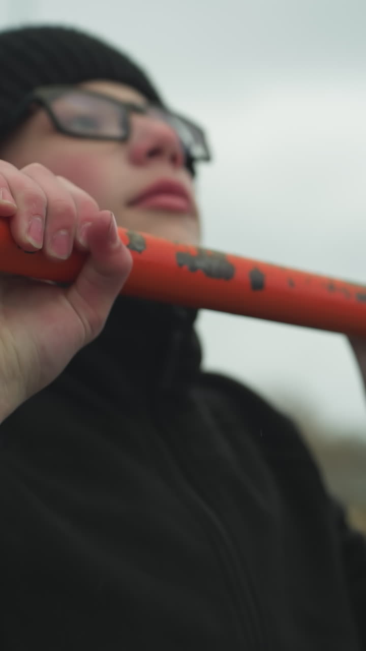 Close-up of a boy working out on pull-up bars in an outdoor gym area, after successfully completing his fourth pull-up, he struggles to continue, with blur background