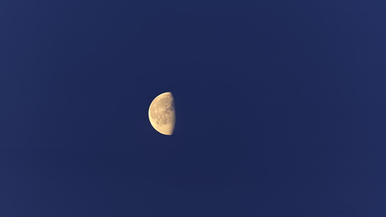 lapso de tiempo de la luna que se levanta de la parte inferior izquierda a la parte superior derecha en el cielo nublado azul oscuro del verano