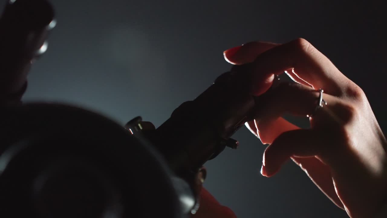 mani che allineano la lente del telescopio per la calibrazione, scatto ravvicinato low-key che cattura le dita con anelli e i segni degli strumenti, rotazione accurata del focheggiatore e del supporto metallico, cavo rosso e riflessi freddi suggeriscono