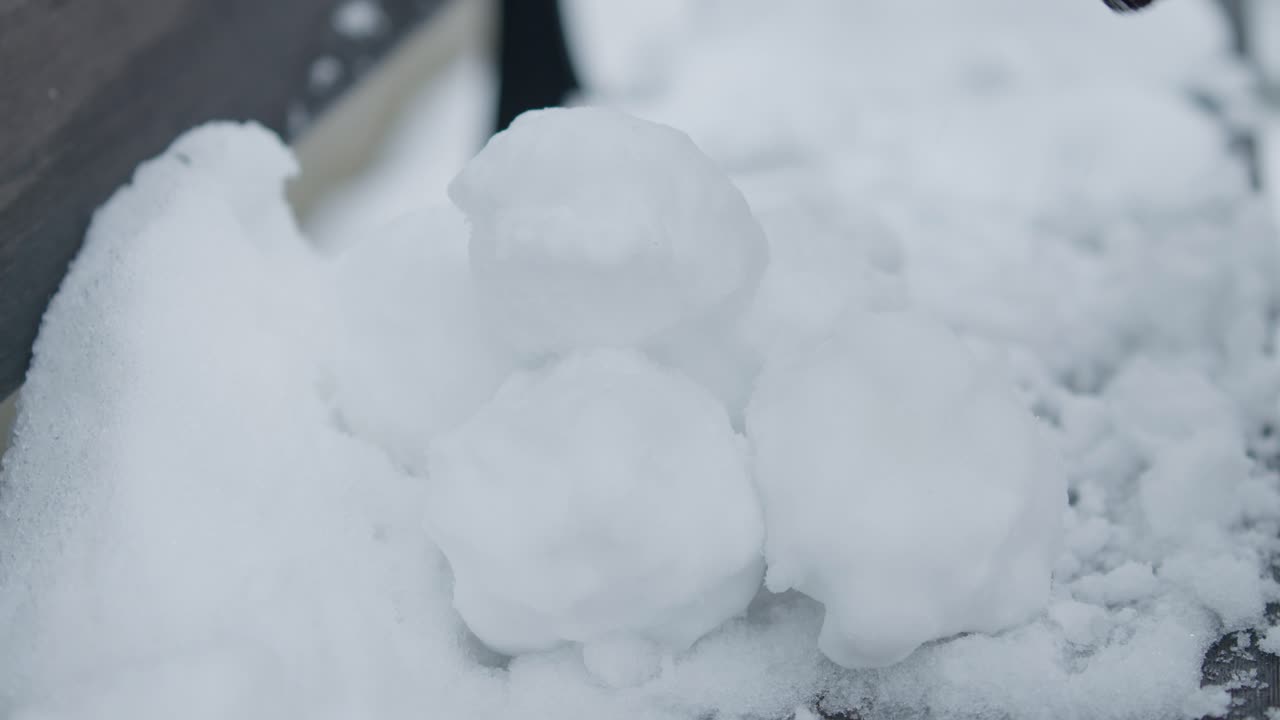 primer plano en cámara lenta de la preparación de una pila de bolas de nieve con guantes negros
