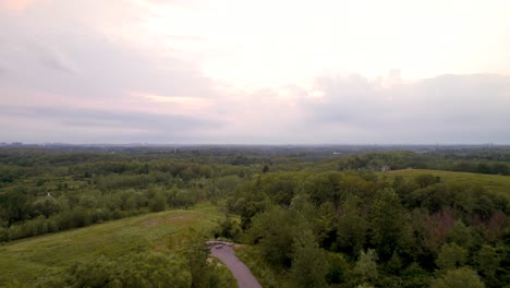 Aerial-View-Flying-Over-Hill-Top-Park-with-Trails-Cloudy-Skies-and-Power-Lines-Beyond