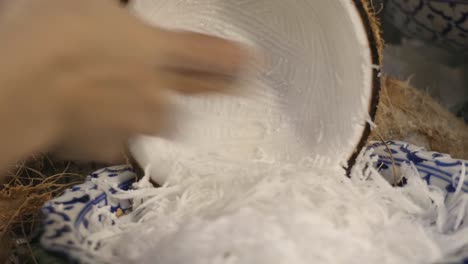 A-video-of-a-person's-hands-grating-coconut-meat-into-a-bowl-for-making-Thai-coconut-macaroon-or-'Khanom-ba-bin'-in-Thai-at-a-food-stall