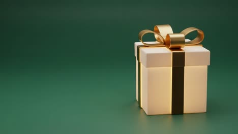 a beautifully wrapped gift box with a golden bow set against a subtle green background, perfect for celebrations and special occasions