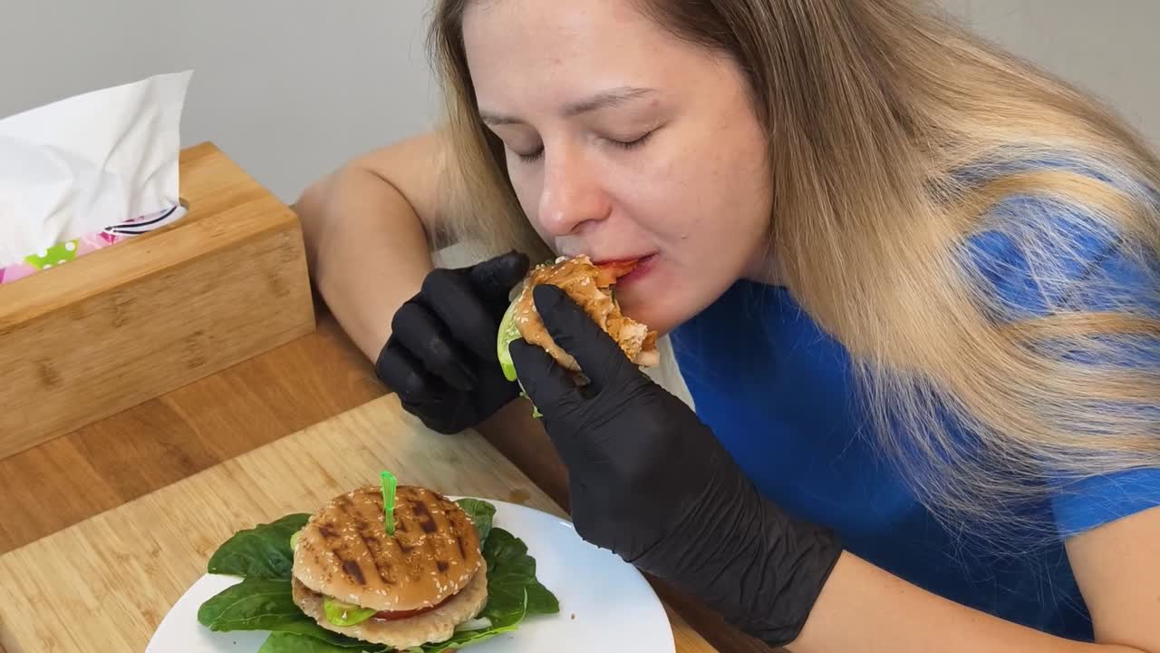 Una mujer comiendo una hamburguesa.