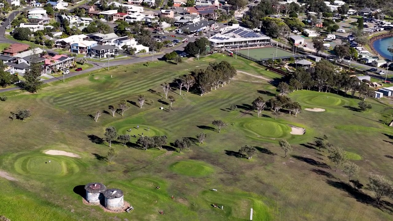 Ripresa aerea con drone dall'alto che esegue una panoramica su un campo da golf verde e un quartiere residenziale in Australia