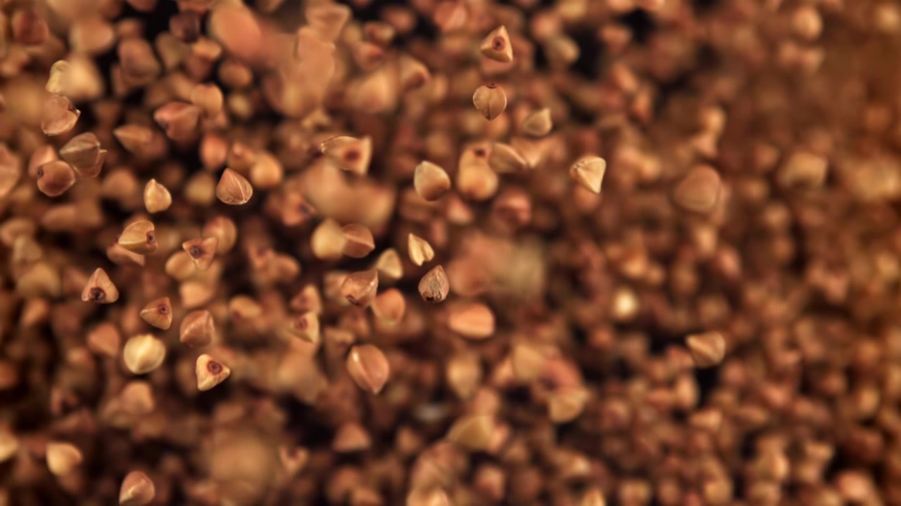 Grani di grano saraceno che cadono al rallentatore con sfondo sfocato