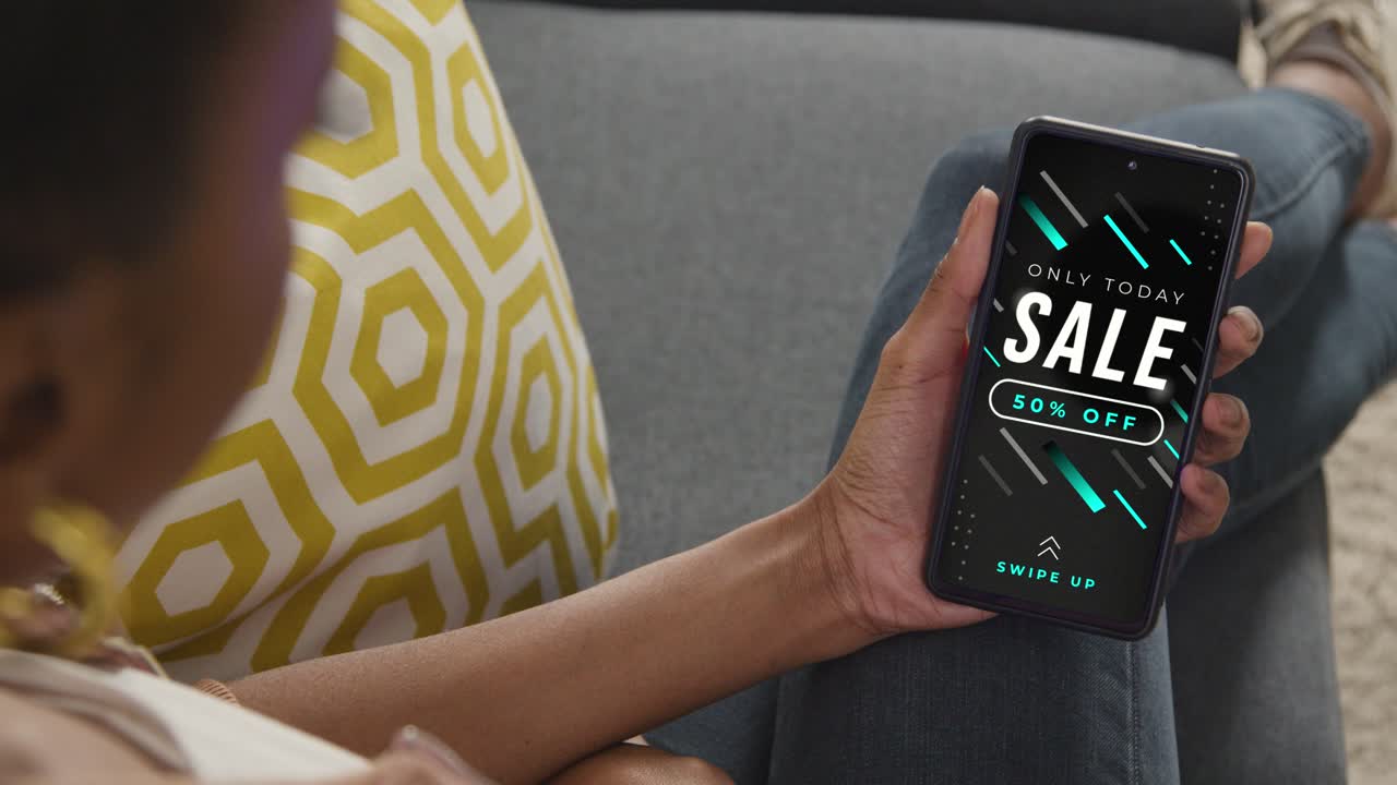 가정에서 소파에 앉아서 휴대 전화로 온라인 판매 거래를 보고 있는 여성의 근접 사진