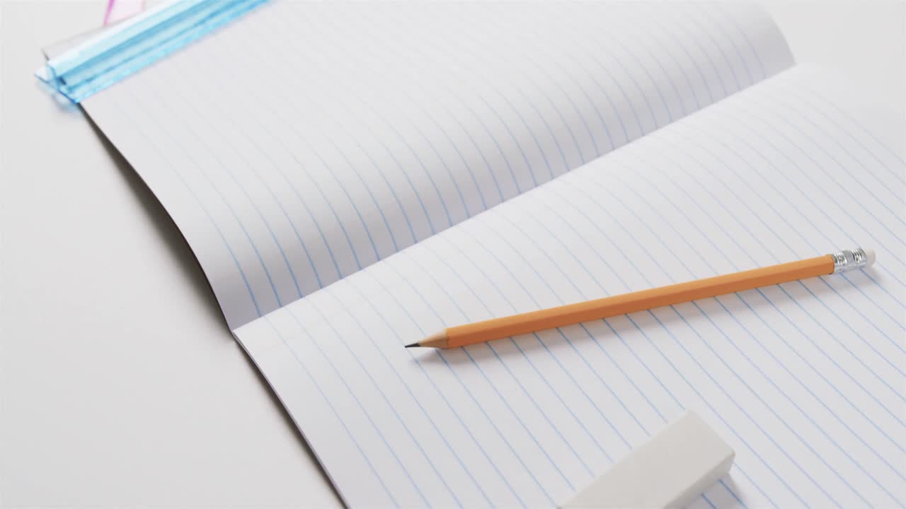 Close up of open notebook with school stationery on grey background, in slow motion