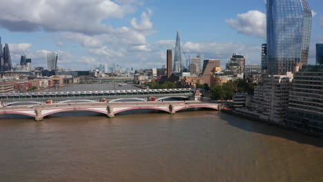 Forwards-ascending-fly-above-River-Thames.-Gradually-revealing-bridges-across-water-and-various-buildings-on-both-banks.-Sunny-day-in-city.-London,-UK