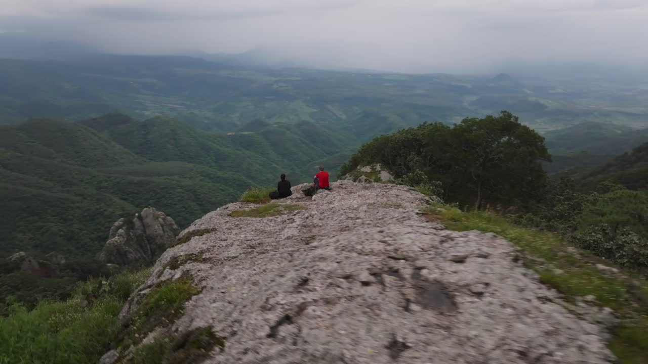 Hikers enjoying the view from a Sierra de Quila cliff overlooking valley in Jalisco, Mexico