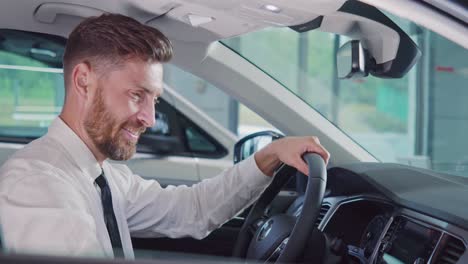 smiling man sitting in new car and showing thumb up