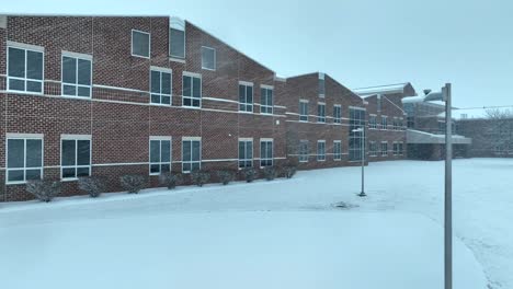 edificio escolar de ladrillo americano cubierto de nieve con grandes ventanas
