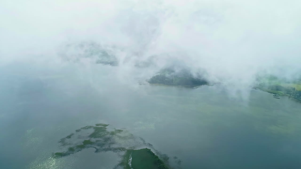 공중 드론 팬은 구름이 많은 날 구름을 통해 볼 수 있는 많은 작은 섬과 함께 큰 호수 위에
