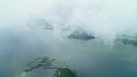 aerial drone pan shot over a large lake with many small islands visible through clouds on a cloudy day