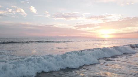 aerial slow motion shot of the white foaming surf of the pacific ocean under a beautiful orange sunset in costa rica