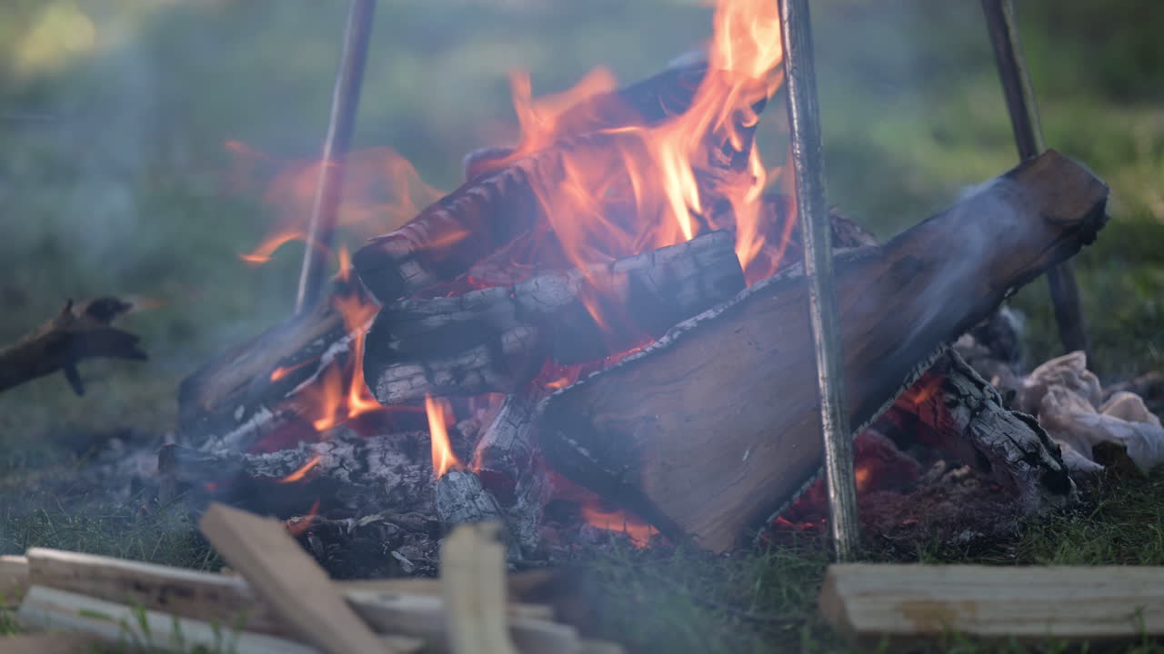 Campfire with burning logs and smoke outdoors