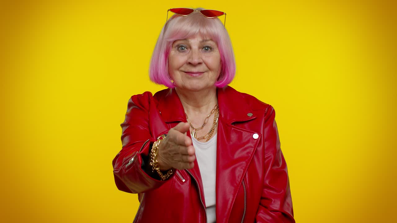 Friendly senior woman outstretching hand to camera, offering handshake, greeting with kind smile