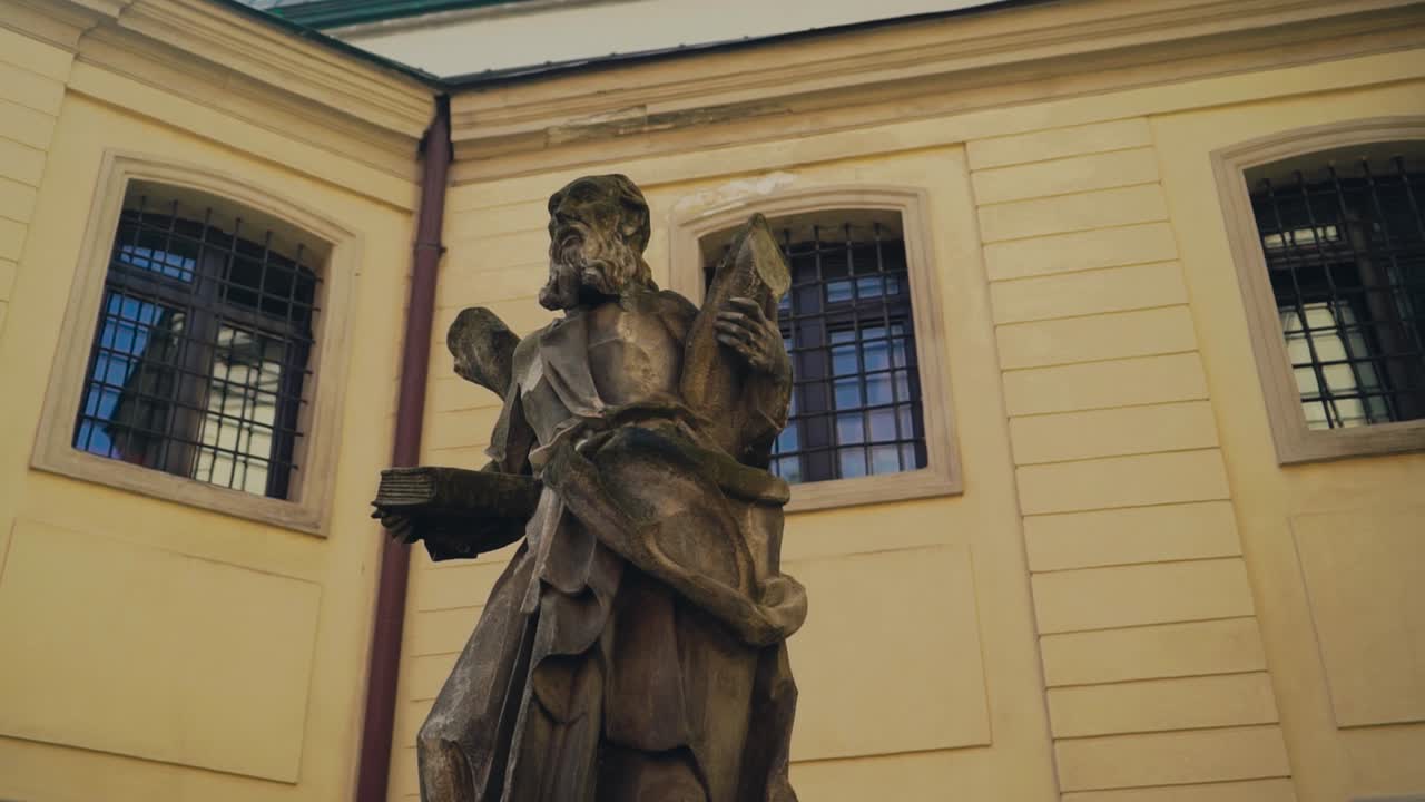 view of the statue of sage with a book in his hands on the background of urban architecture. Close-up. Camera motion around the monument