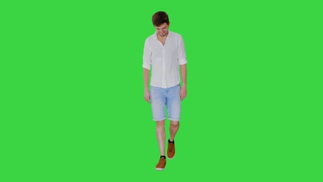 casual young man walking and looking forward on a green screen, chroma key