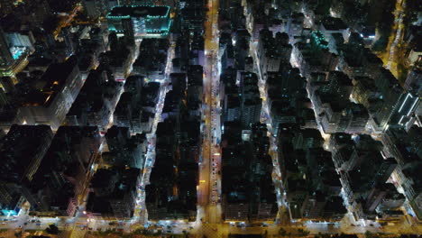 drone overhead of street traffic, residential buildings, and rooftops at night in hong kong