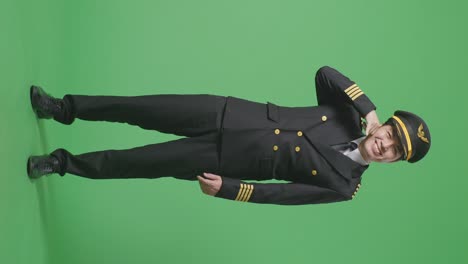 full body of asian man pilot smiling and making call me gesture to camera while standing in the green screen background studio