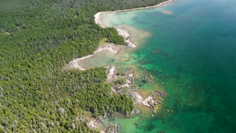 Aerial-top-down-pan-of-jagged-green-coastline,-Lake-Huron-wilderness,-Michigan