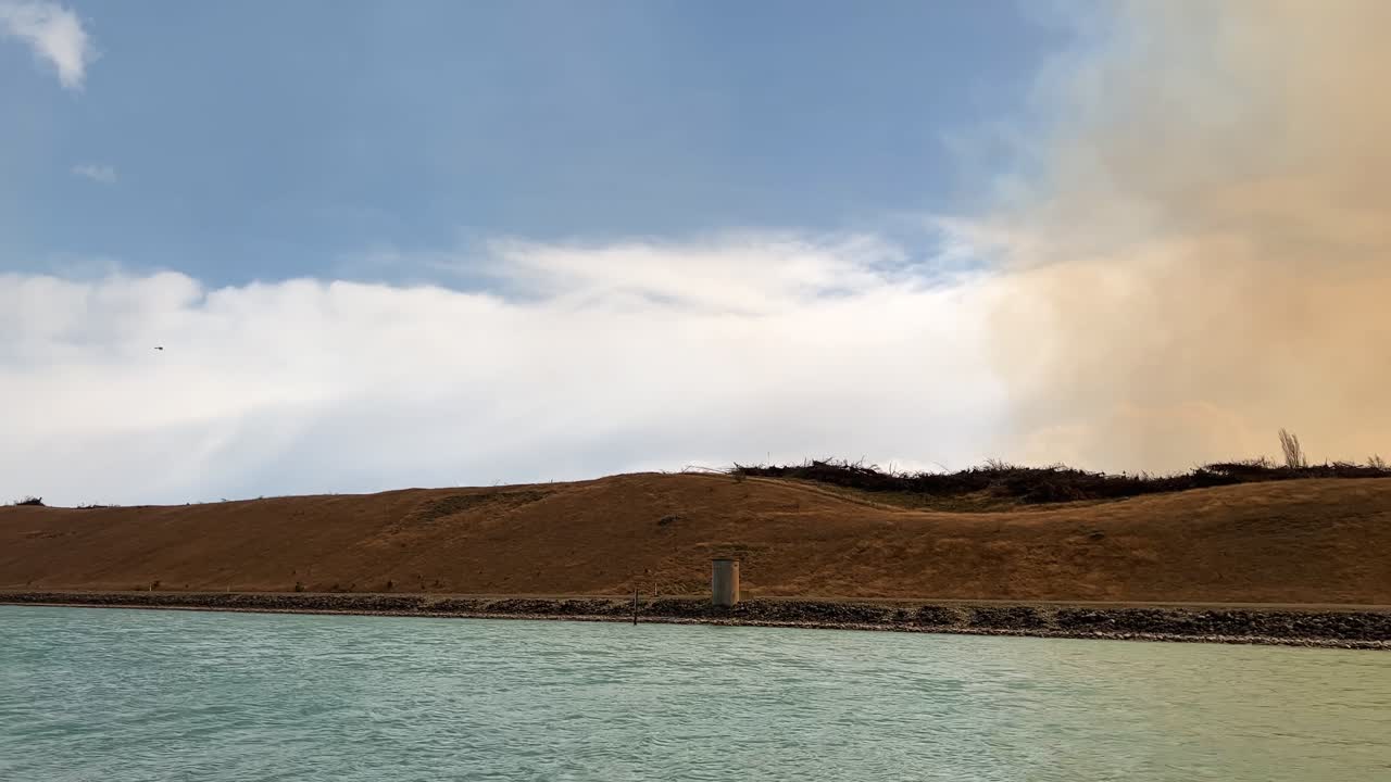 humo de incendios forestales que cubre el cielo por encima de los canales hidroeléctricos de pukaki causando luz solar naranja