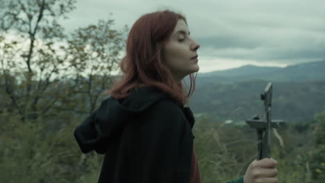 woman walks among trees with crucifix of jesus in hand praying christianity