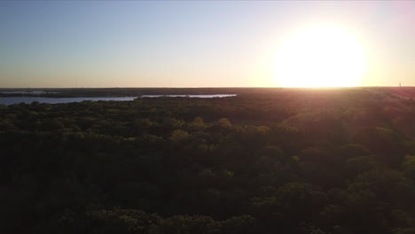 Backwards-dolly-shot-over-a-lake-and-forest-during-sunset