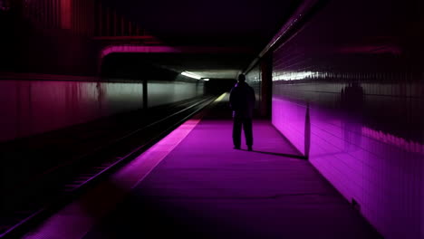 solitary figure on a neon-lit subway platform