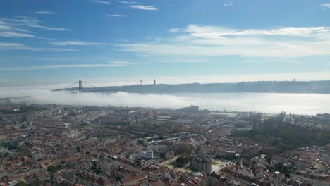 Foggy-Tranquility:-Static-Shot-Revealing-the-Mystical-Atmosphere-Below-Lisbon-Bridge,-with-a-Scattering-of-Clouds-in-the-Sky