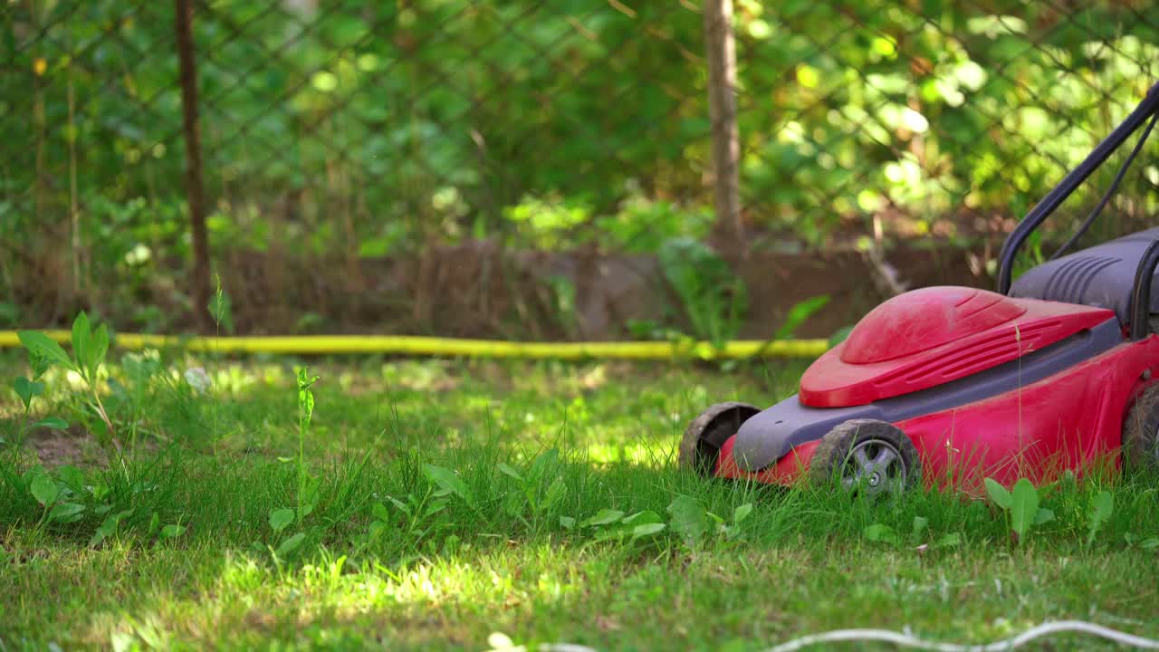 Garden equipment. Worker cutting grass with electric lawn mower. Lawn mower on green grass at working process.