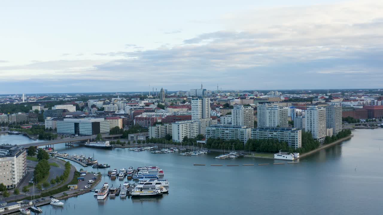 panorámica aérea lenta de edificios altos y barcos a lo largo del paseo marítimo de helsinki al atardecer, finlandia