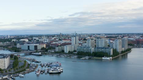 slow aerial pan of tall buildings and boats along helsinki waterfront at dusk, finland