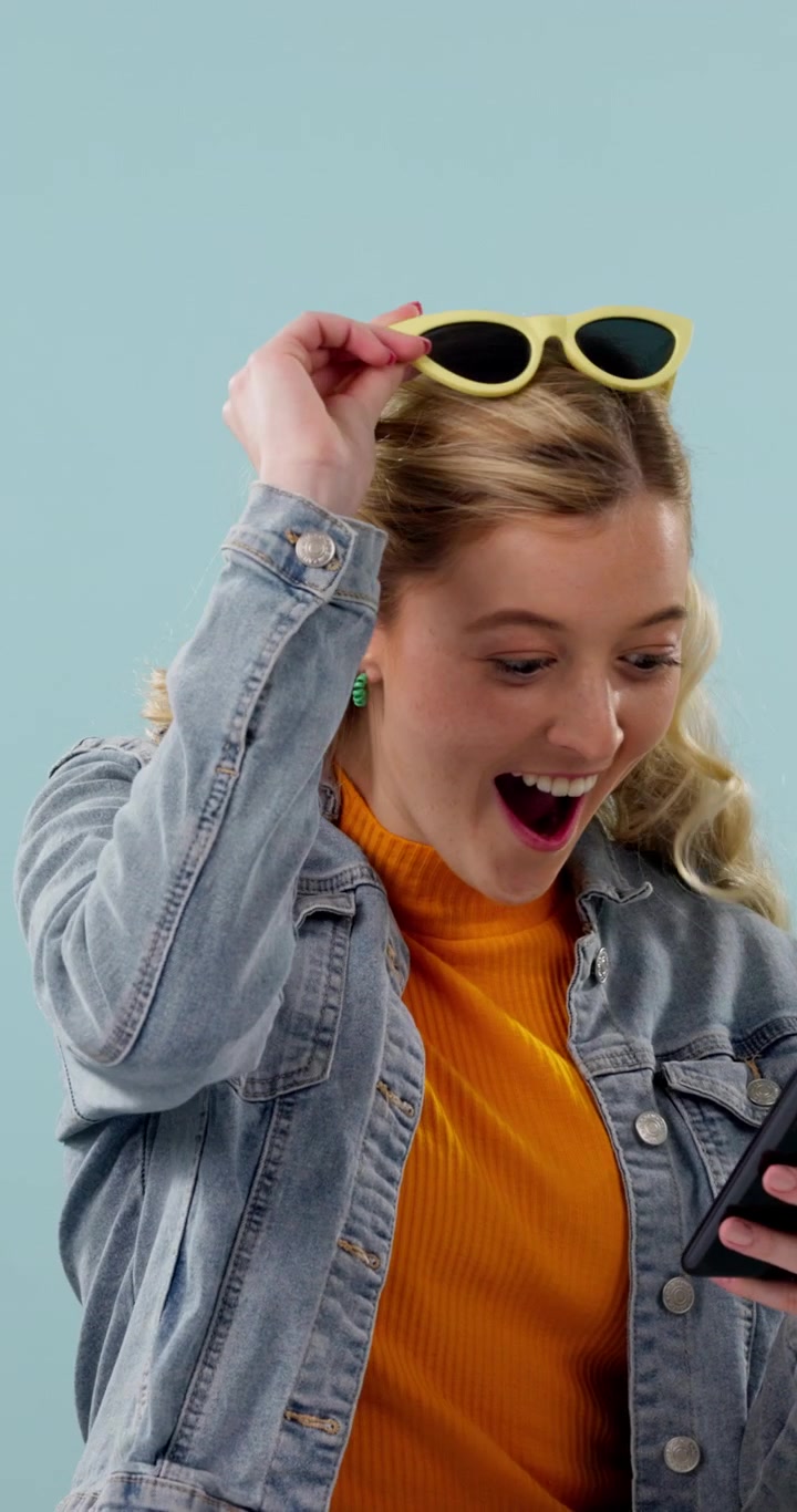 Young Woman Reacting With Excitement to News on Her Smartphone