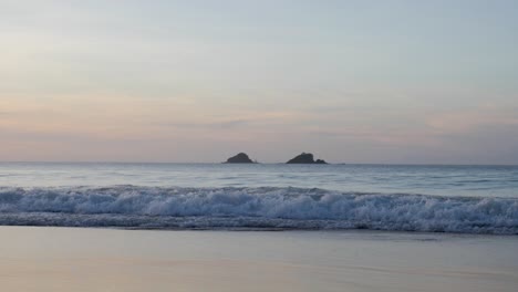 Toma-En-Cámara-Ultra-Lenta-De-Olas-Rompiendo-Y-Moviéndose-En-La-Playa-Con-Un-Hermoso-Cielo-Colorido-Al-Atardecer-En-Asia