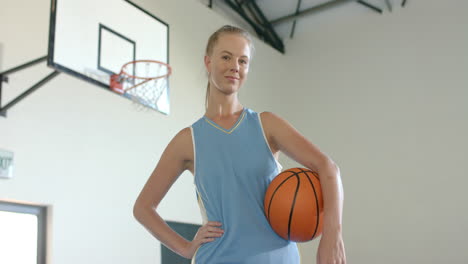 holding basketball, confident woman standing in gymnasium, ready for game