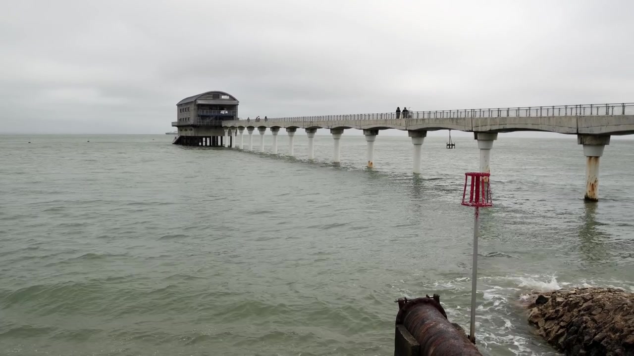 Ripresa a mano della stazione di salvataggio RNLI di Bembridge, del molo e del mare in una giornata nuvolosa