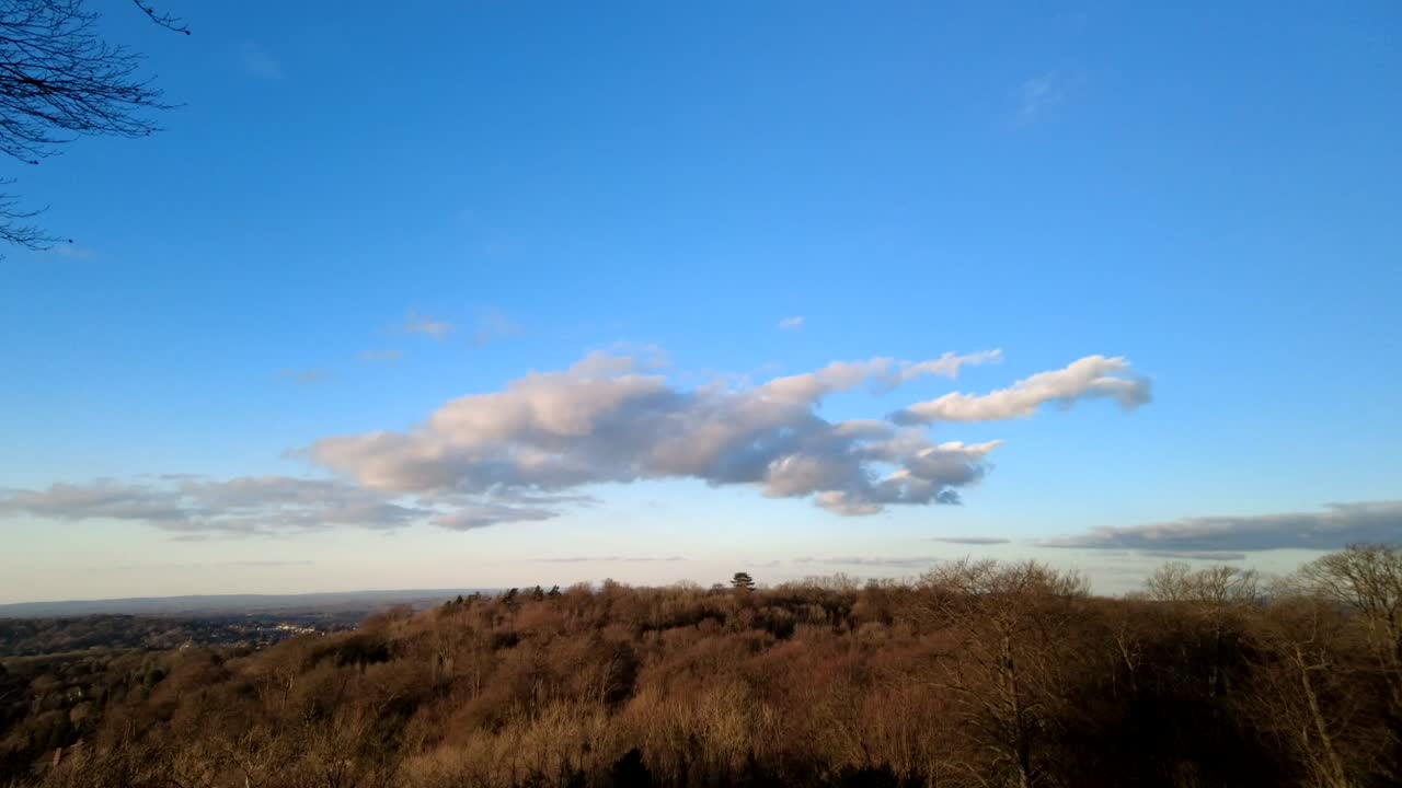 pan izquierda time-lapse capturando la danza de las nubes al anochecer sobre un bosque