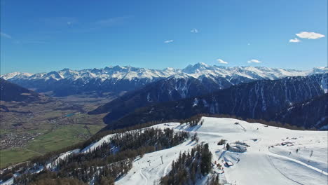 Skiing-resort-on-mountain-top-and-small-town-bellow,-aerial-view