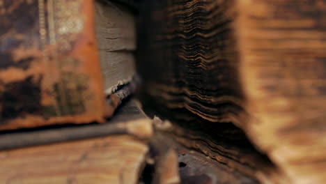 Extreme-close-up-pan-of-sides-of-worn-ancient-books,-shallow-DOF