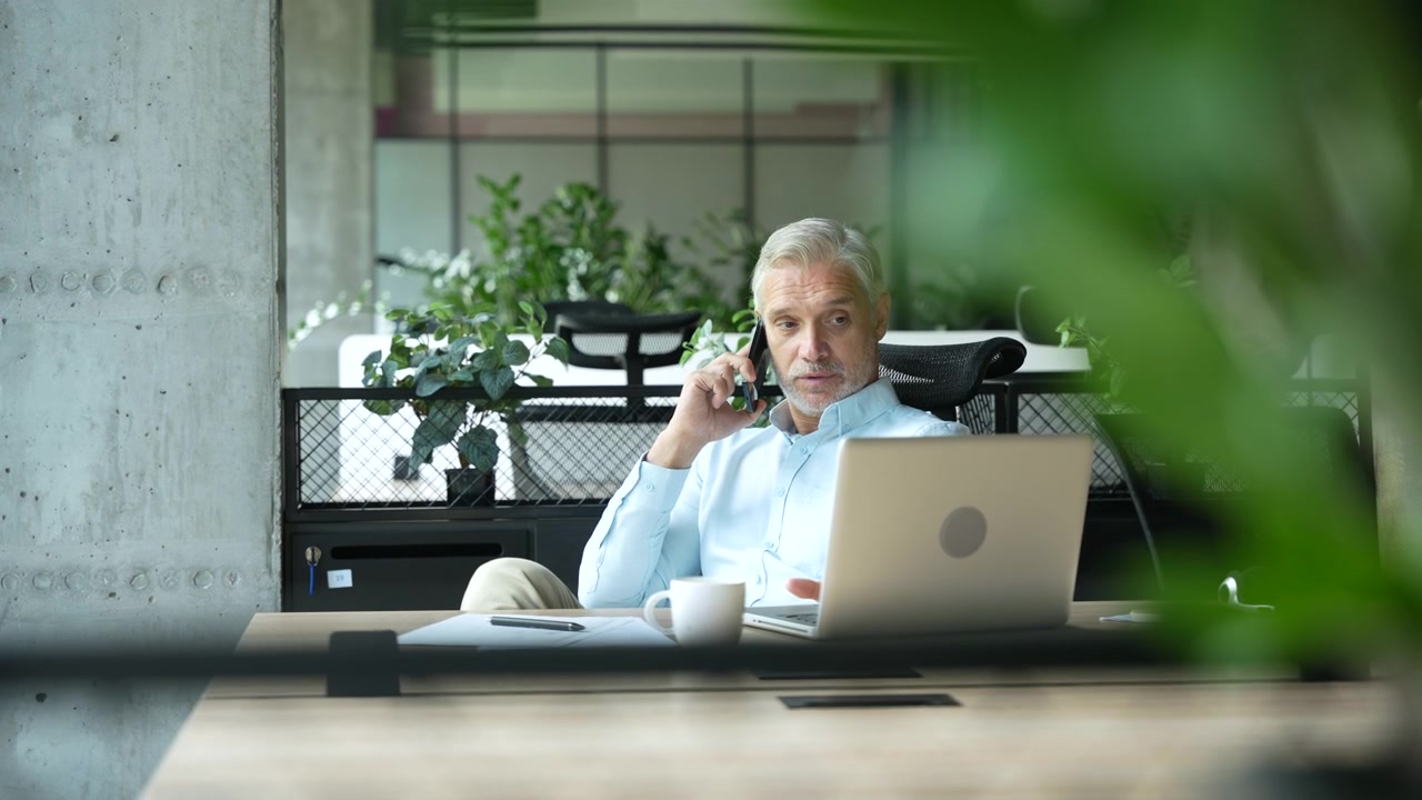 Moden forretningsmand taler i smartphone på moderne kontor