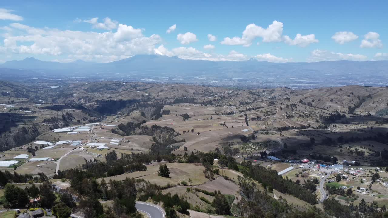 Spettacolare volo di drone in 4K che cattura la valle di Saquisilí nella provincia di Cotopaxi, Ecuador, con i vulcani Cotopaxi e Rumiñahui contro cieli azzurri e nuvole alla deriva